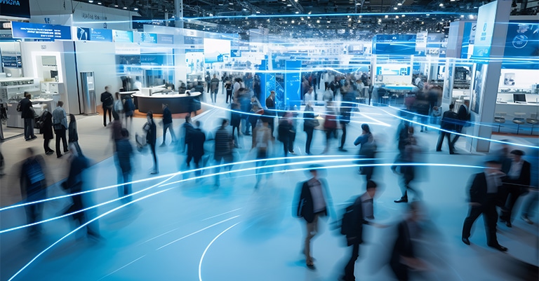Trade Show Booth Tips: The Ultimate List for Success 7 A bustling trade show floor with people moving through a dynamic, futuristic space highlighted by glowing blue lines.