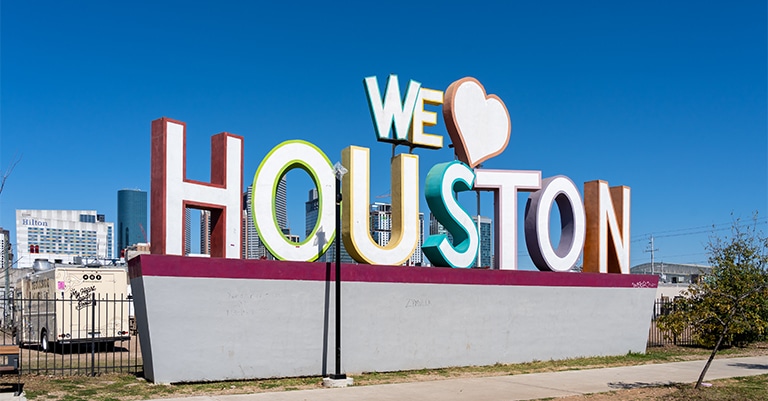Top Trade Show Cities in the US: The Ultimate List 10 The colorful "We Love Houston" sign set against a clear blue sky with downtown Houston skyscrapers in the background.