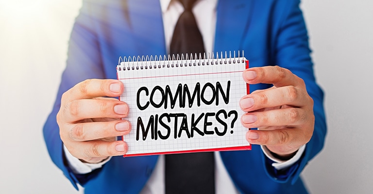 Pharmaceutical Trade Show Hospitality: The Complete Guide 10 A person in a blue suit holds a small notepad that reads "COMMON MISTAKES?". This graphic supports pharmaceutical trade show hospitality content by signaling a discussion of planning errors, missed opportunities, or compliance issues to avoid.