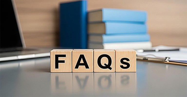 Pharmaceutical Trade Show Hospitality: The Complete Guide 11 Wooden letter blocks on a desk spell "FAQS" with books, a laptop, and office materials blurred in the background. This graphic supports pharmaceutical trade show hospitality content by signaling a section that answers common questions about planning, compliance, services, or event logistics.